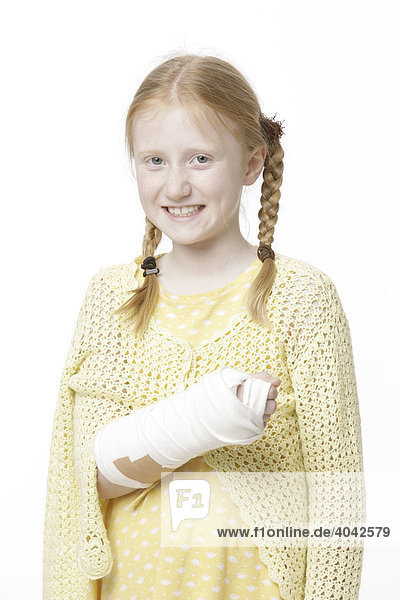8-jähriges Mädchen mit Haarzöpfen und gebrochenem Arm in Gips  lacht