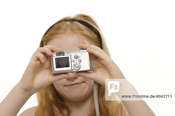 8-year-old red-haired girl taking pictures of herself with a digital camera