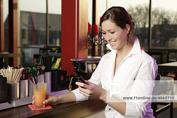 Young woman in a cafe bar looking at her cell phone