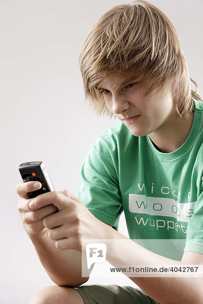 13-jähriger Junge mit grünem T-Shirt  spielt mit Handy