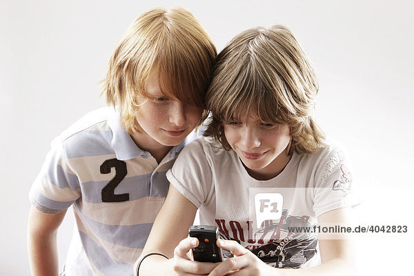 Zwei 12-jährige Jungen spielen mit Handy.