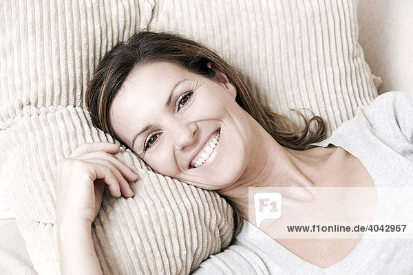Woman lying against a sofa cushion