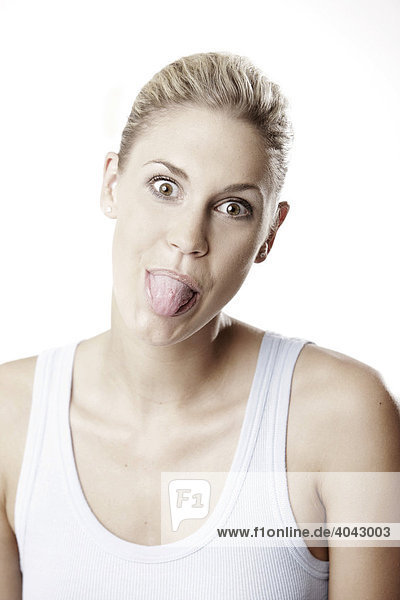 Blonde Frau im hellblauen Top  streckt Zunge raus