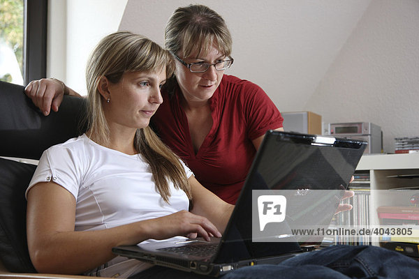 2 Frauen surfen im Internet mit Laptop Computer in ihrer Wohnung