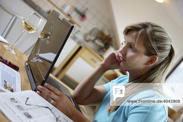 Junge Frau  25-30 Jahre  surft mit Laptop Computer im Internet am Küchentisch