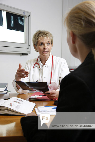 Ärztin spricht mit einer Patientin im Arztzimmer in einem Krankenhaus