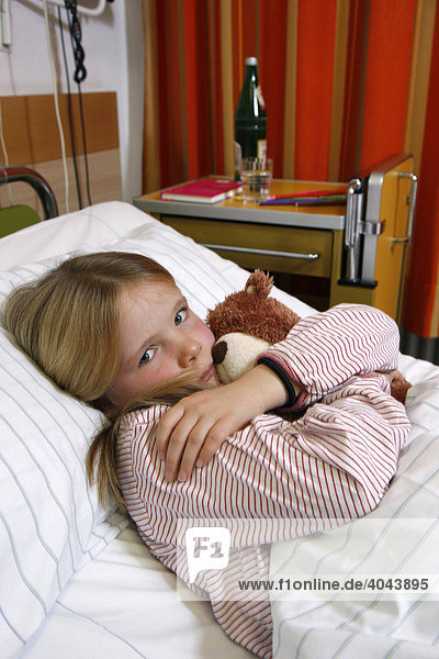 Girl  7 years  with teddy in a hospital bed
