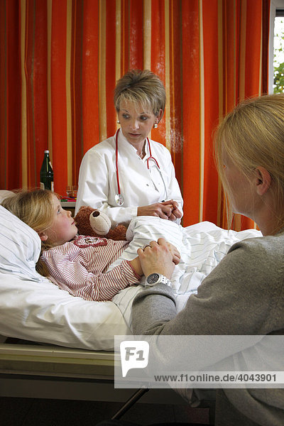 Ärztin spricht mit einer jungen Patientin  7 Jahre  und ihrer Mutter am Krankenbett in einem Krankenhaus