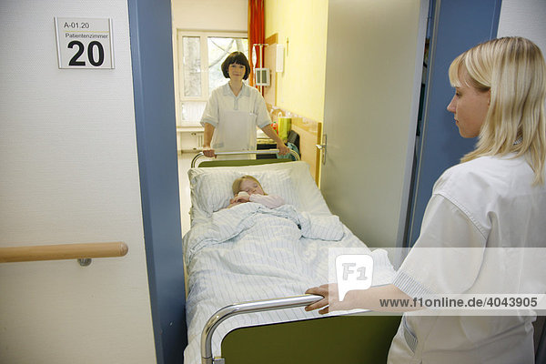 Krankenschwestern schieben eine junge Patientin über den Stationsflur eines Krankenhauses