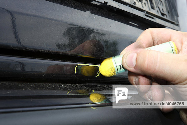 Hand marking a damaged part of a car