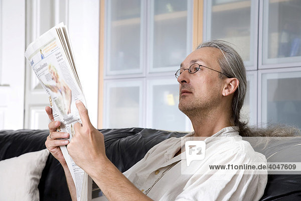 Mann liest auf Sofa Zeitung