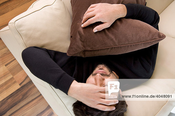 Man with a headache sleeping on a sofa