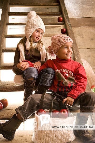 Zwei Geschwister-Kinder sitzen auf der Treppe einer Wanderhütte