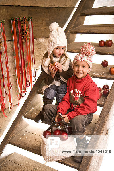 Zwei Geschwister-Kinder sitzen auf der Treppe einer Wanderhütte