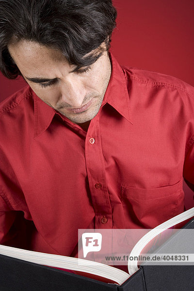 Man wearing a red shirt holding a book