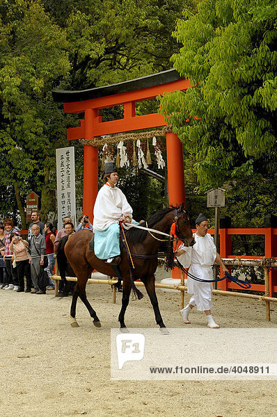 Reiter vor einem japanischen heiligen Tor  Tori  bei einem rituellen Pferderennen im Kamigamo Schrein beim Aoi Fest in Kyoto  Japan  Asien