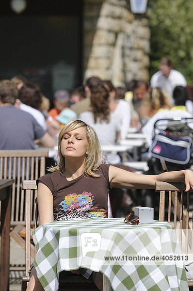 Junge blonde Frau sitzt in Café  sonnt sich  Sommer