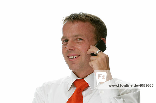 Businessman wearing a shirt and red tie making a call on his mobile phone and smiling happily