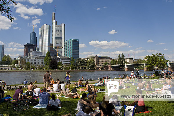 Mainufer mit Menschen in der Sonne  hinten Bankenviertel mit Commerzbank Frankfurt  Hessen  Deutschland  Europa