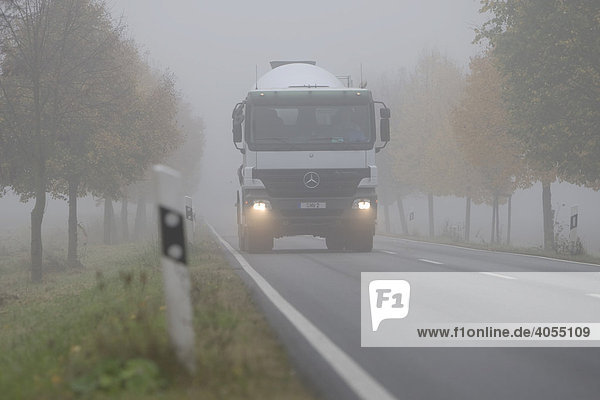 Ein LKW fährt mit Abblendlicht auf einer Landstraße in dichtem Nebel  Hessen  Deutschland  Europa