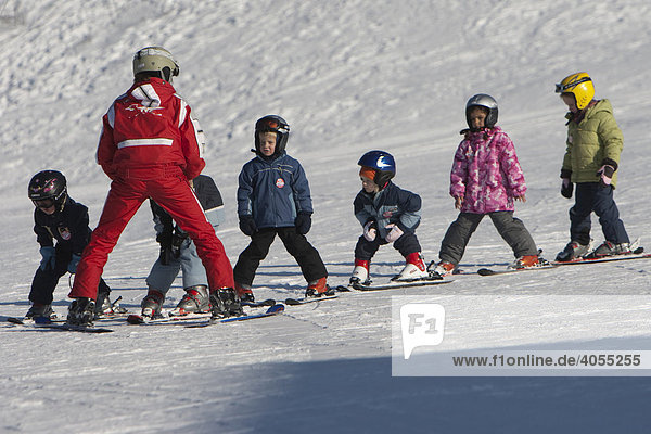 Children being taught by a ski instructor in a beginners course in a ski school and skiing down a mountain-slope  Ehrwald  Tyrol  Austria  Europe