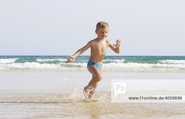 Boy  4 years  running in the small waves on the beach of Fuerteventura with delight  Canary Island  Spain  Europe
