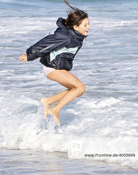 Girl  8 years  jumping and running in the waves on the beach of Fuerteventura  Canary Island  Spain  Europe