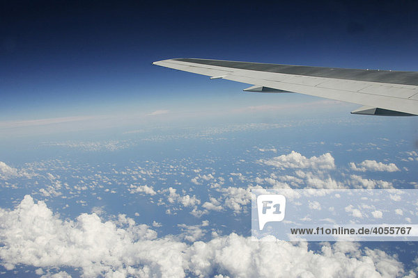 Tragfläche eines Flugzeuges über Schäfchenwolken