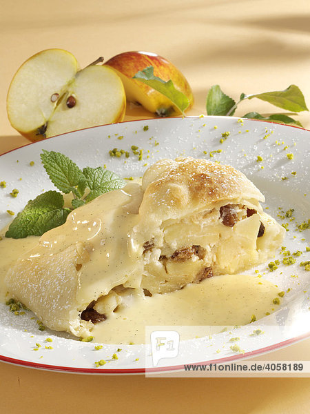 Apple strudel made from sheet pastry with vanilla sauce with pieces of pistachio and a mint garnish  apple halves