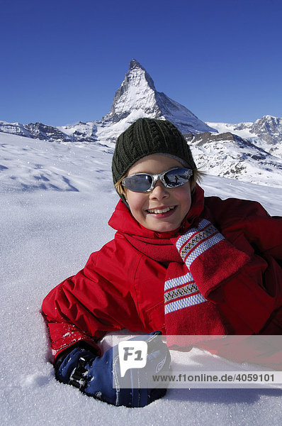Boy lying in snow in front of the Matterhorn  Zermatt  Wallis or Valais  Switzerland  Europe