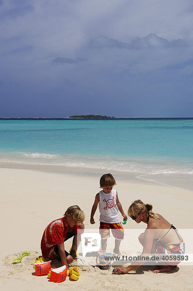 Woman and two children playing on the beach  Laguna Resort  The Maldives  Indian Ocean