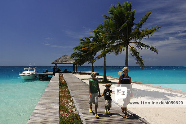 Woman and two children walking along the jetty  Laguna Resort  The Maldives  Indian Ocean