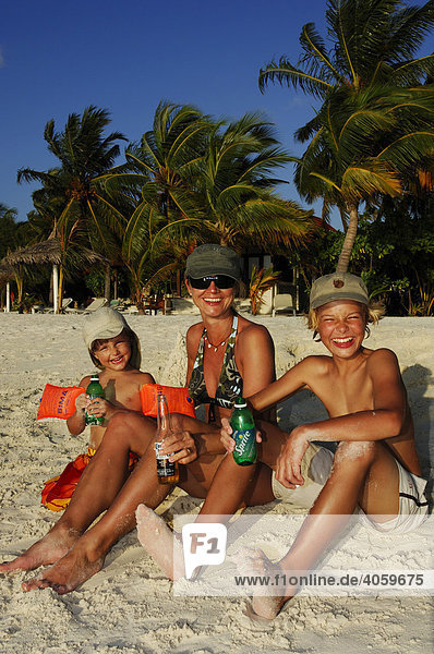 Frau mit zwei Kindern am Strand mit Getränken  Kurumba Resort  Malediven  Indischer Ozean
