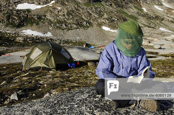 Wanderin mit Fliegennetz liest Buch  Ikasartivaq-Fjord  Ostgrönland  Grönland