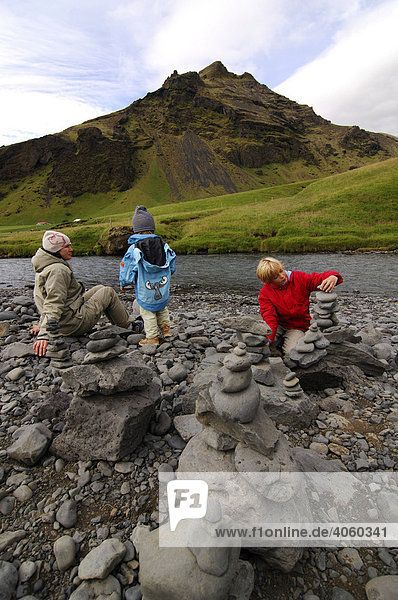 Frau und zwei Kinder bauen Steinmänner am Skogafoss  Island  Europa