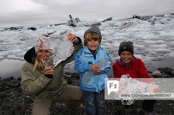 Frau und zwei Kinder mit Gletschereisbrocken  Joekulsarlon  Island  Europa
