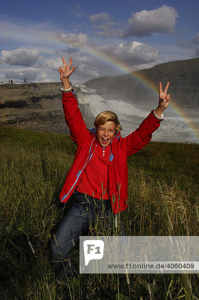Kind jubelt unter Regenbogen am Gullfoss Goldener Wasserfall Island Europa