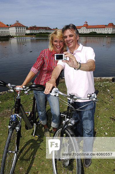 Best Ager  Fahrradfahrer fotografieren sich bei Radtour vor Schloss Nymphenburg  München  Bayern  Deutschland  Europa