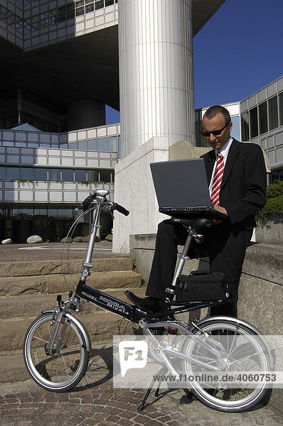 Businessman mit Faltrad auf dem Weg zur Arbeit  Hypobank-Hochhaus  Bogenhausen  München  Bayern  Deutschland  Europa