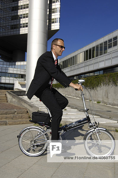 Businessman mit Faltrad auf dem Weg zur Arbeit  Hypobank-Hochhaus  Bogenhausen  München  Bayern  Deutschland  Europa