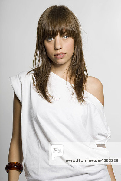 Dark-haired woman wearing a white top  grey backdrop