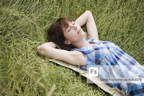 Young dark-haired woman lying in tall grass
