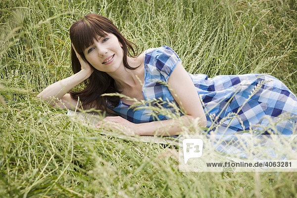 Young dark-haired woman lying in tall grass