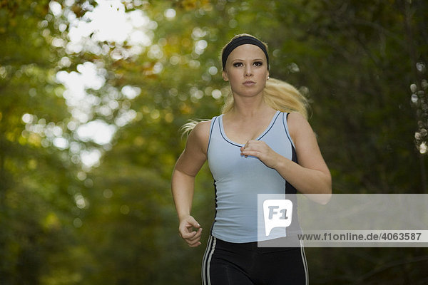 Junge Frau beim Lauftraining im herbstlichen Wald