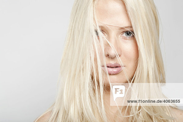 Haarsträhnen im Gesicht einer jungen blonden Frau