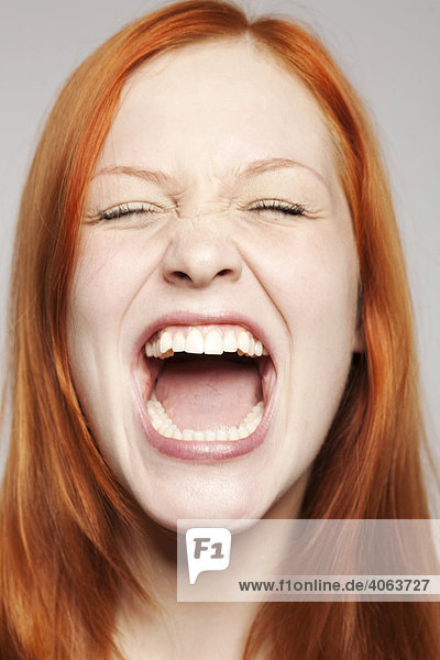Portrait of a young  screaming red-haired woman