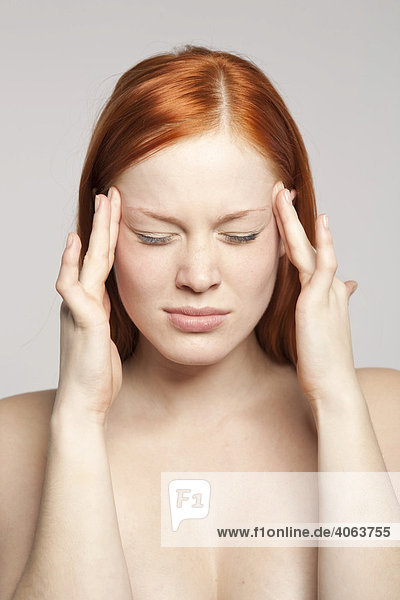 Junge rothaarige Frau mit Kopfschmerzen  Migräne