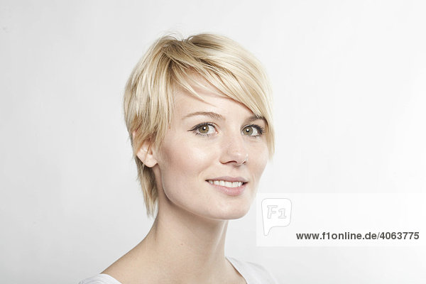 Junge blonde Frau mit kurzen Haaren lächelt freundlich in die Kamera