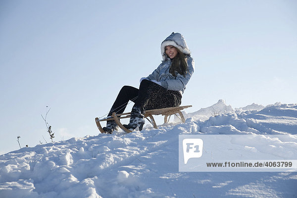 Junge Frau fährt mit einem Schlitten im Schnee