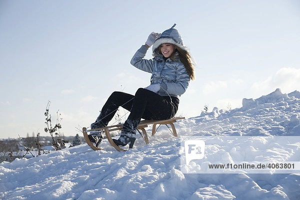Junge Frau fährt mit einem Schlitten im Schnee